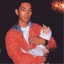 Young Ryuichi Sakamoto holding a orange and white tabby cat